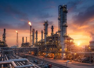 La tensión energética global y el Estrecho de Ormuz: factores de presión que reconfiguran el tablero petrolero internacional Complejo refinador de petróleo durante el atardecer, representando el mercado energético global y su impacto geopolítico.